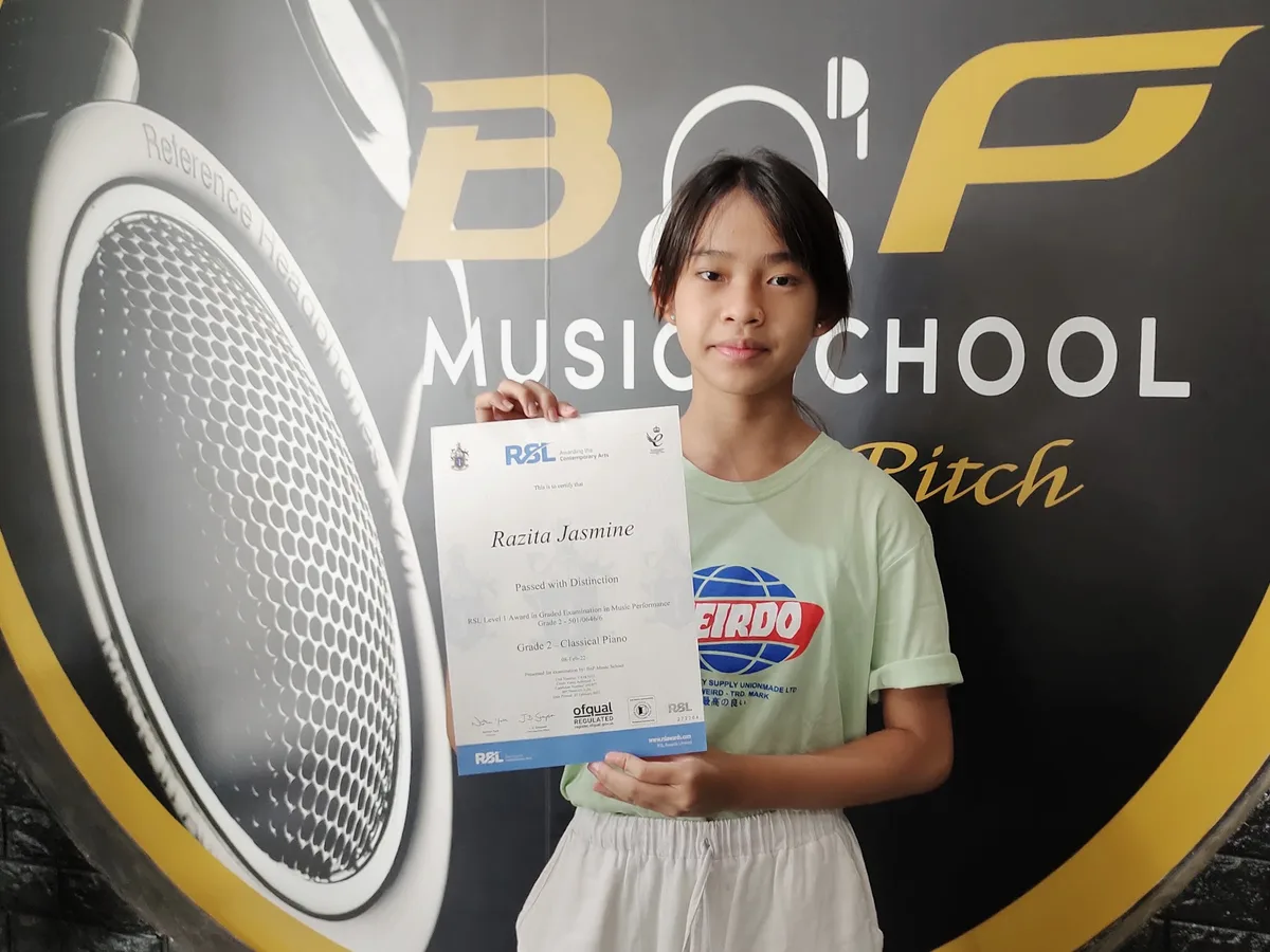 Murid BnP Music School memegang sertifikat RSL Awards yang baru diterimanya